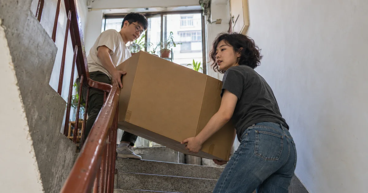 租客和朋友將紙箱搬上新住處樓梯